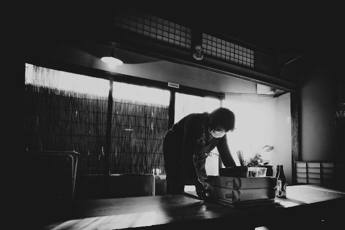 Person wearing mask arranging items in a dimly lit room.